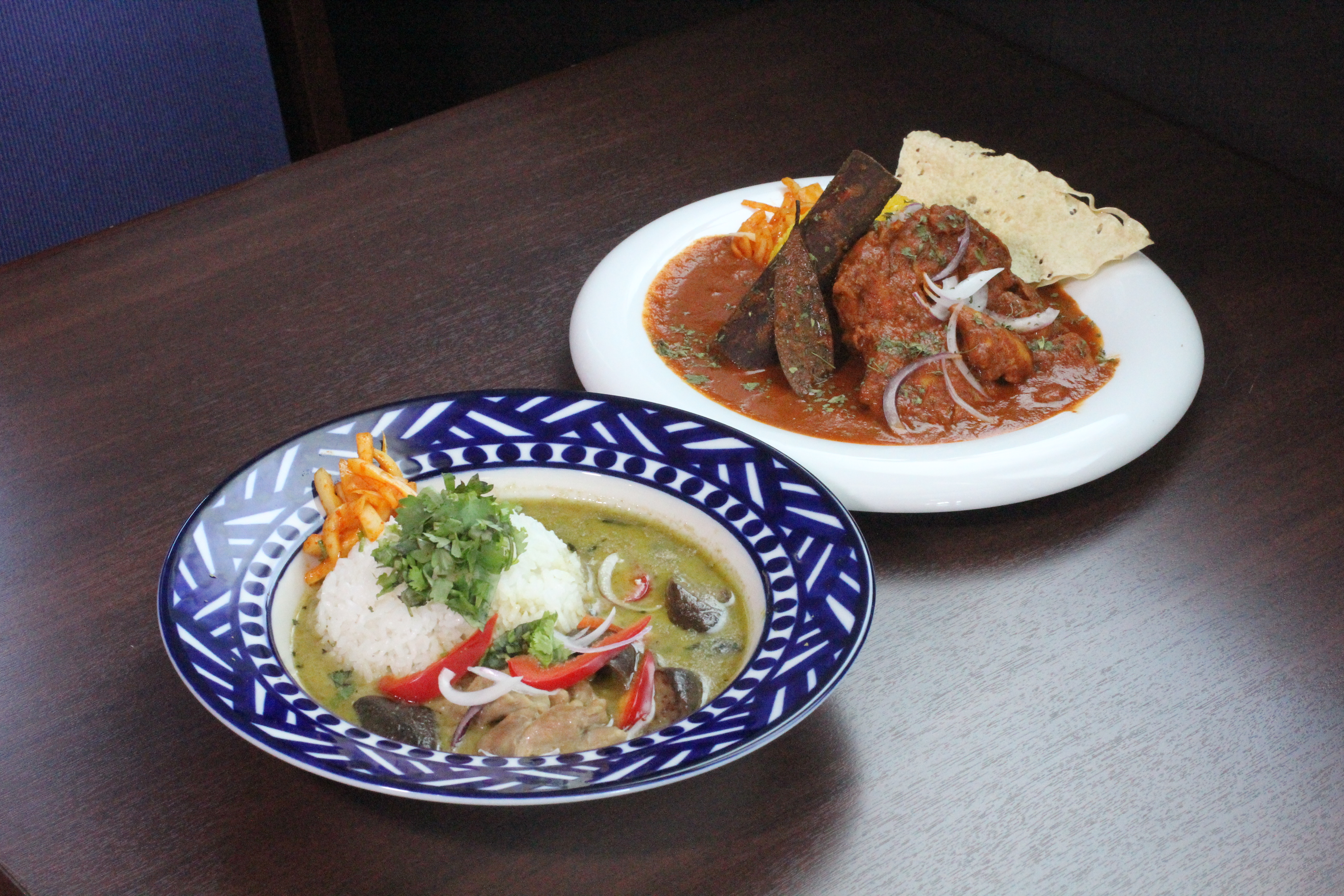 グリーンカレー(左) 1000円(税込) ナスと鶏肉をメインに、スパイスとハーブが効いた一番人気のカレー。 タンドリーバターチキンカレー(右) 1200円(税込) 食べ応えのある鶏肉に、さっぱりとしたトマトの酸味とスパイスの旨味がマッチした一品。